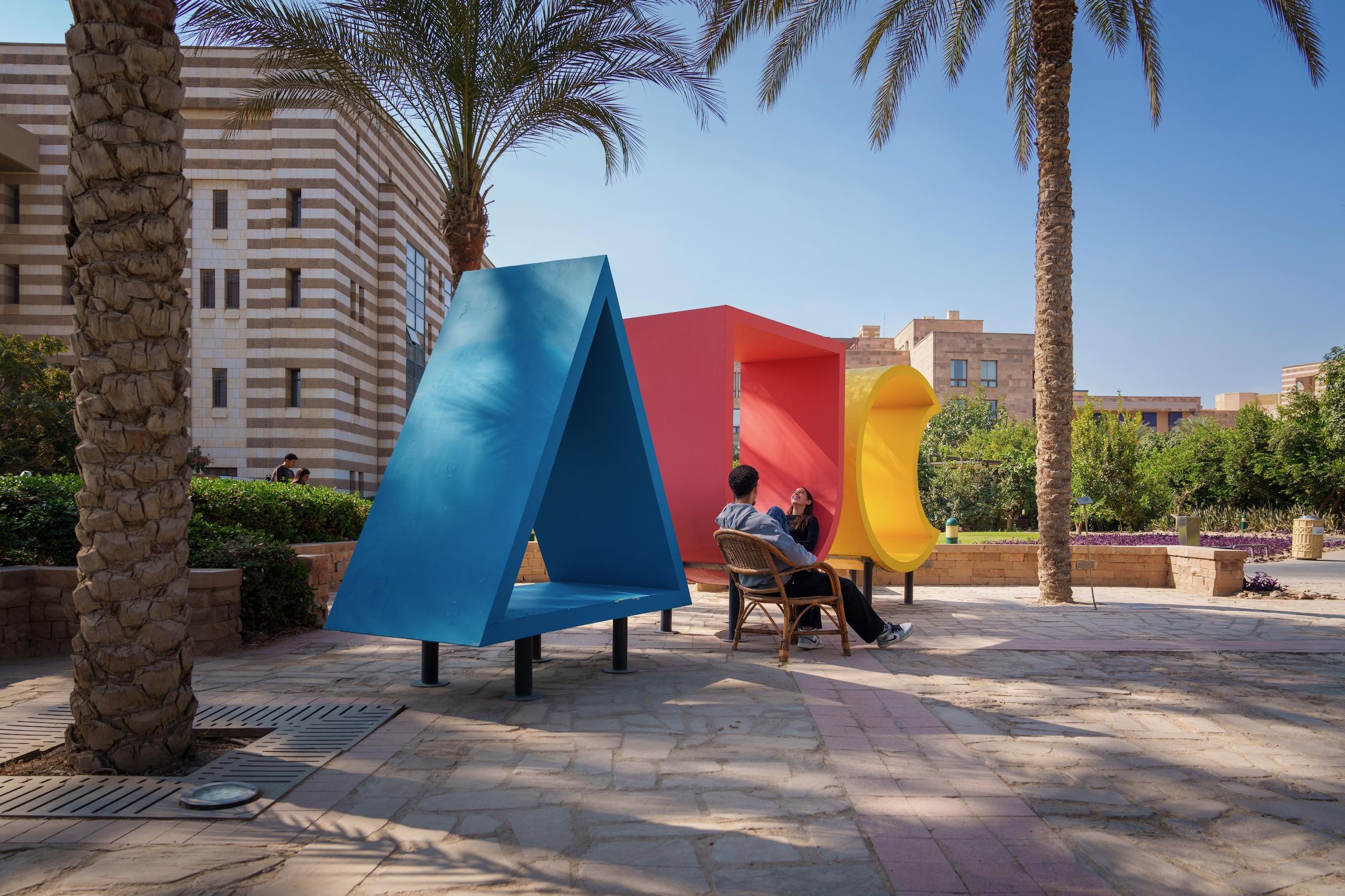 two students sitting inside the AUC monogram