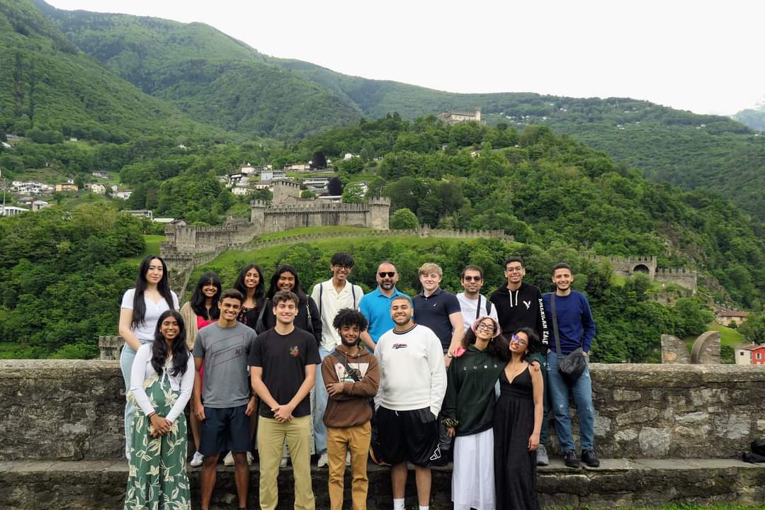 A group of students pose in front of green mountains