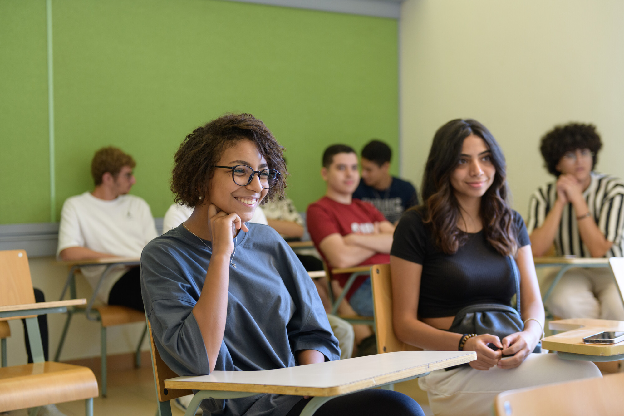 A girl with short hair sitting in a classroom smiling