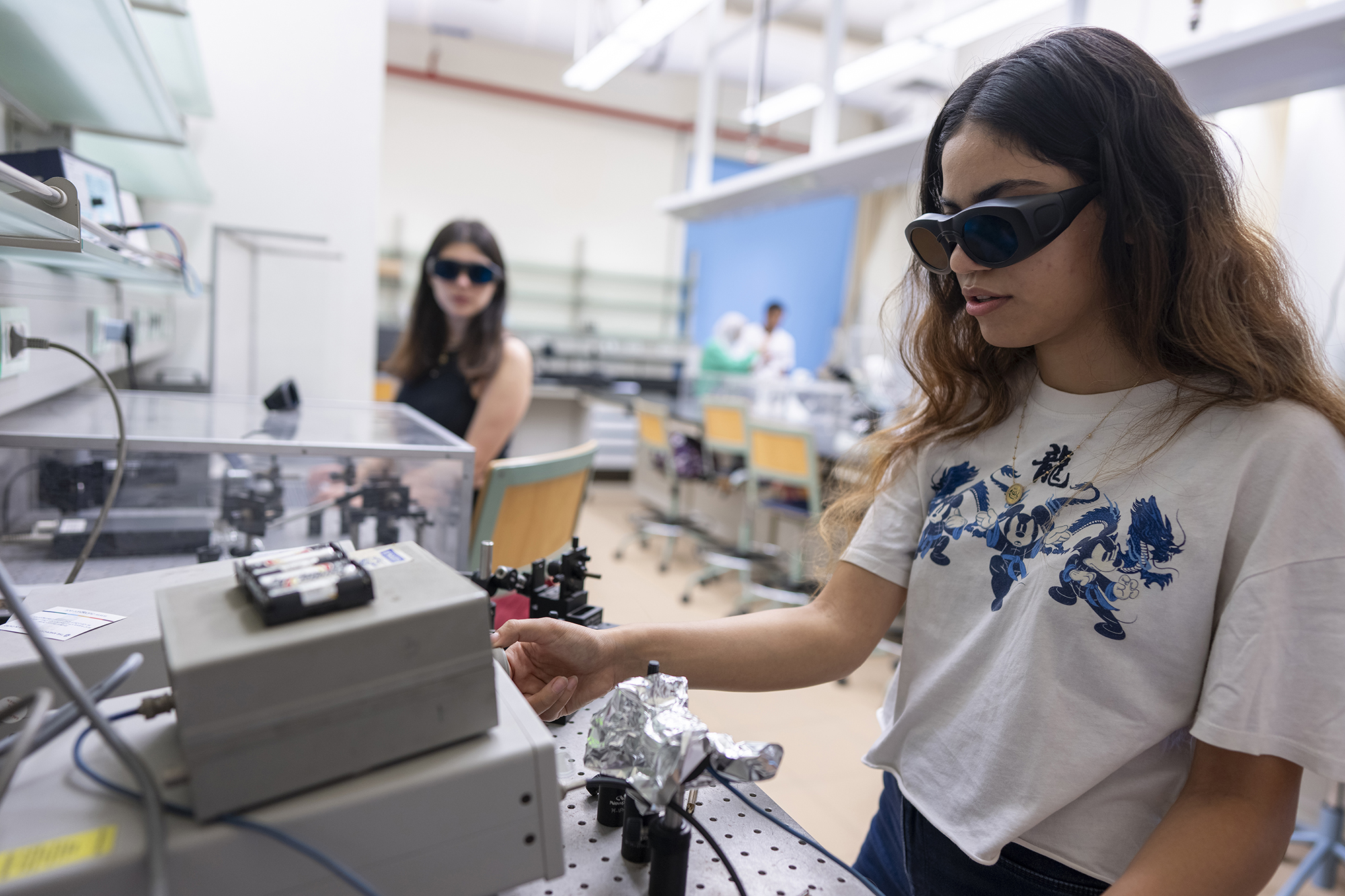 Two girls wearing black goggles in an experiment lab