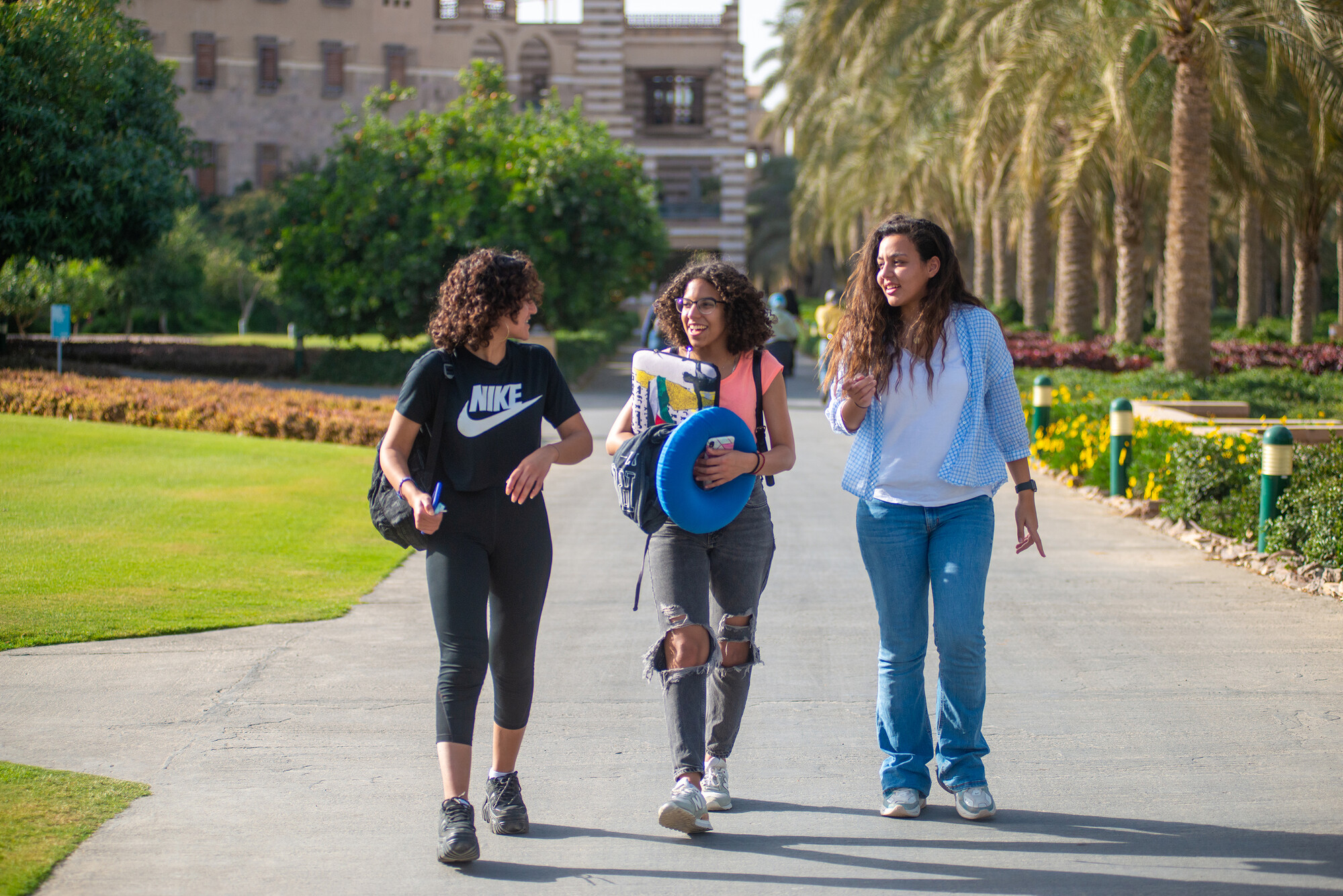 three girls walking at AUC New Cairo campus smiling