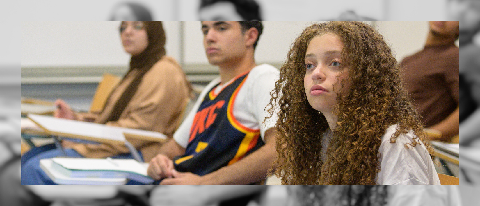 Students in class sitting at their desks and looking straight