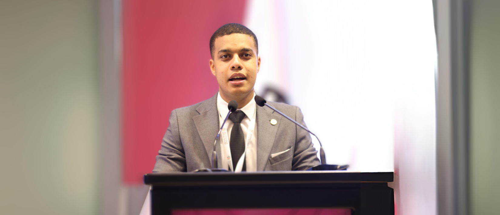 Student wearing a suit and speaking at a podium