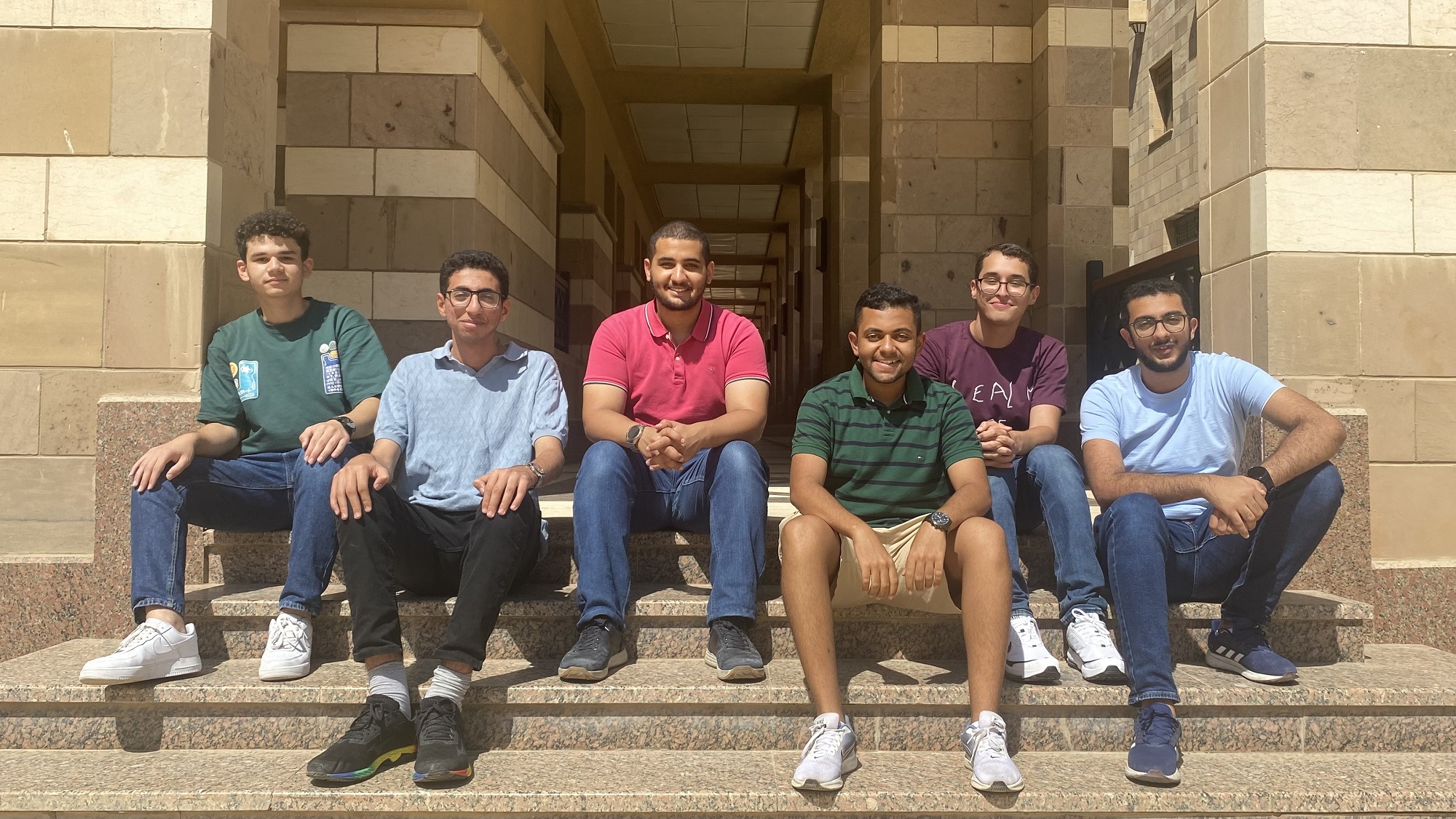 Six males sitting on outdoor stairs 