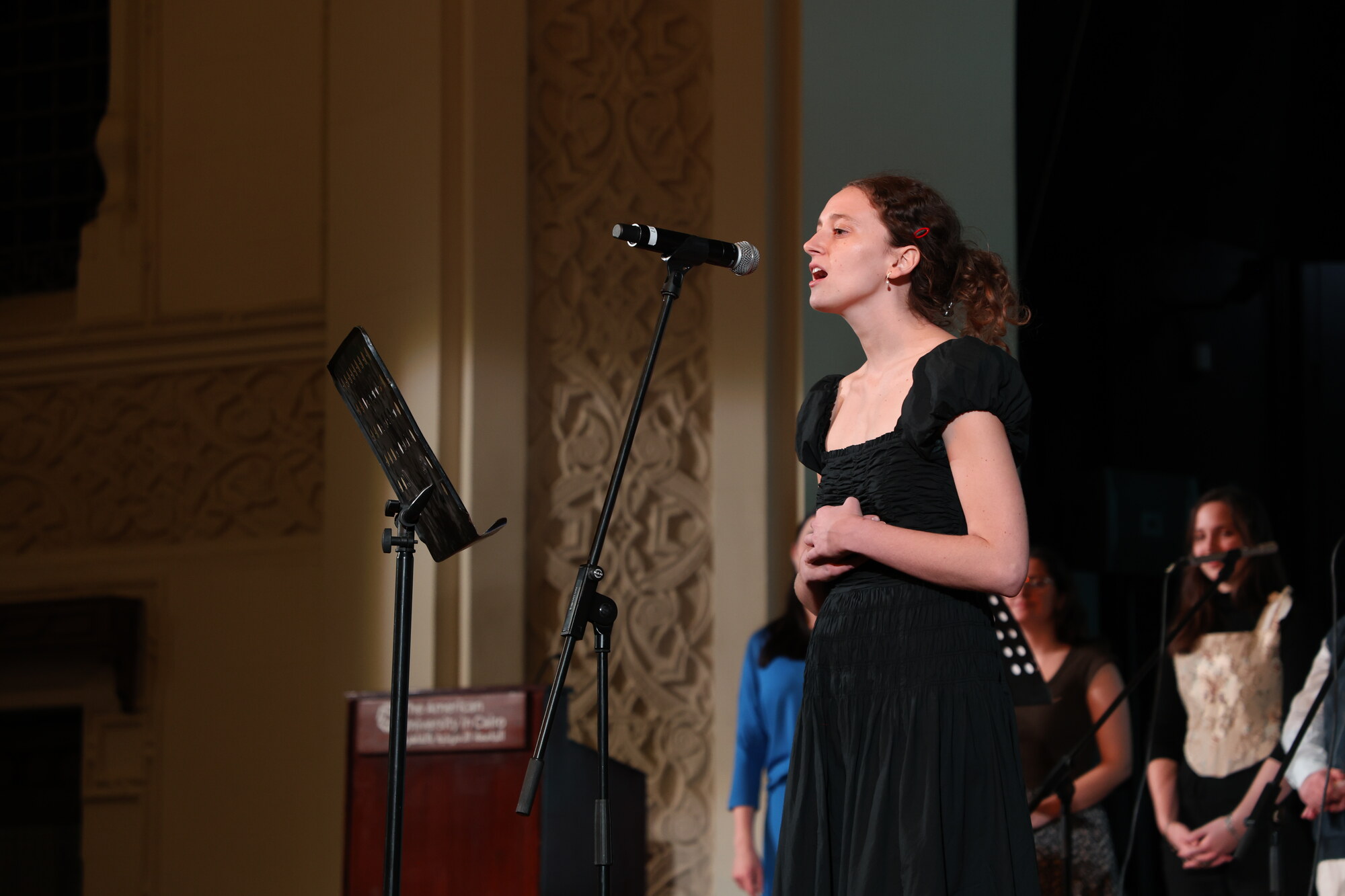 student singing in front of microphone in a concert at AUC ewart hall