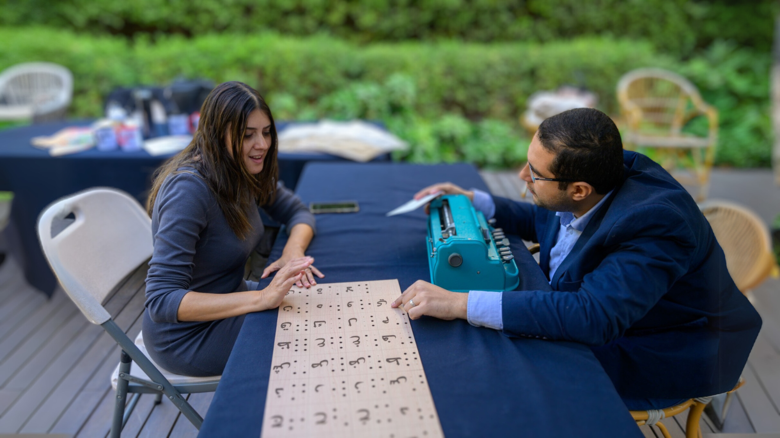 A man and a woman explore a wooden plank translating the Arabic alphabet into braille