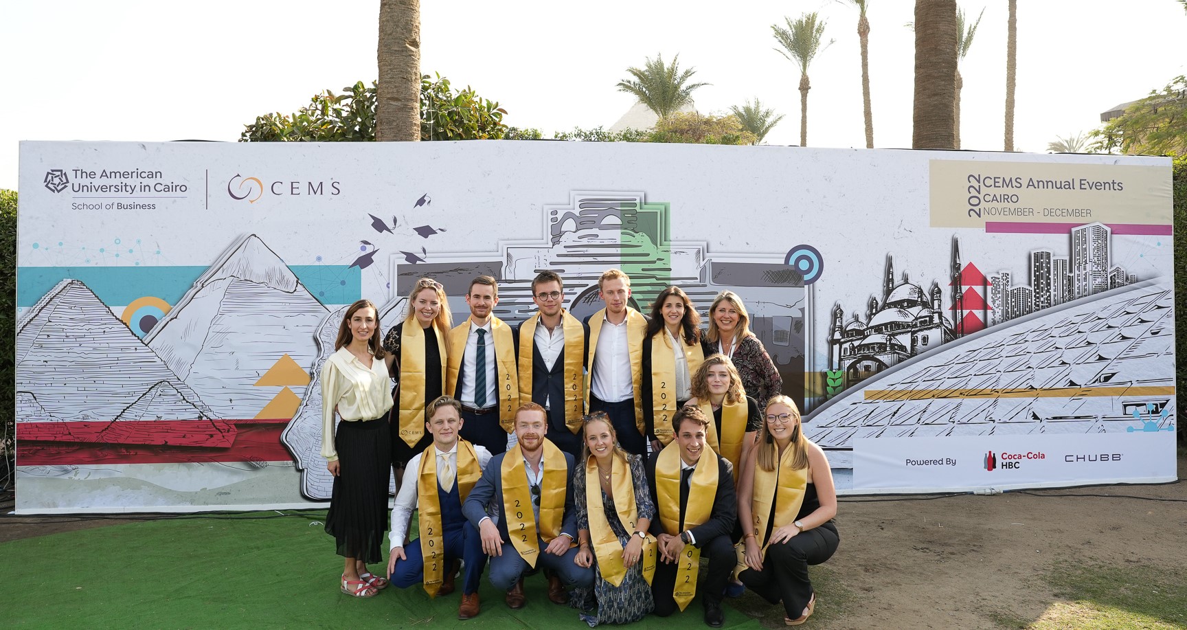 a group of girls and boys wearing yellow sash in a graduation photo