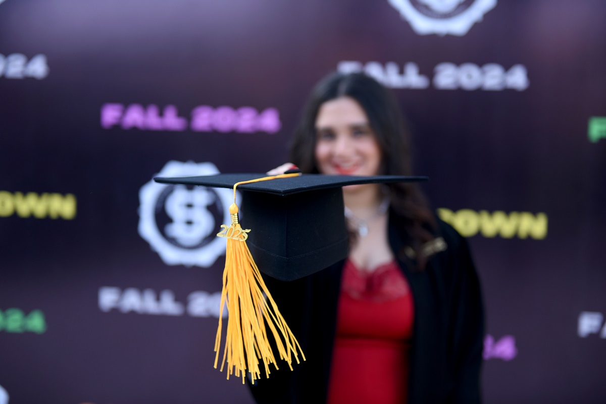 A female is holdnig her graduation cap