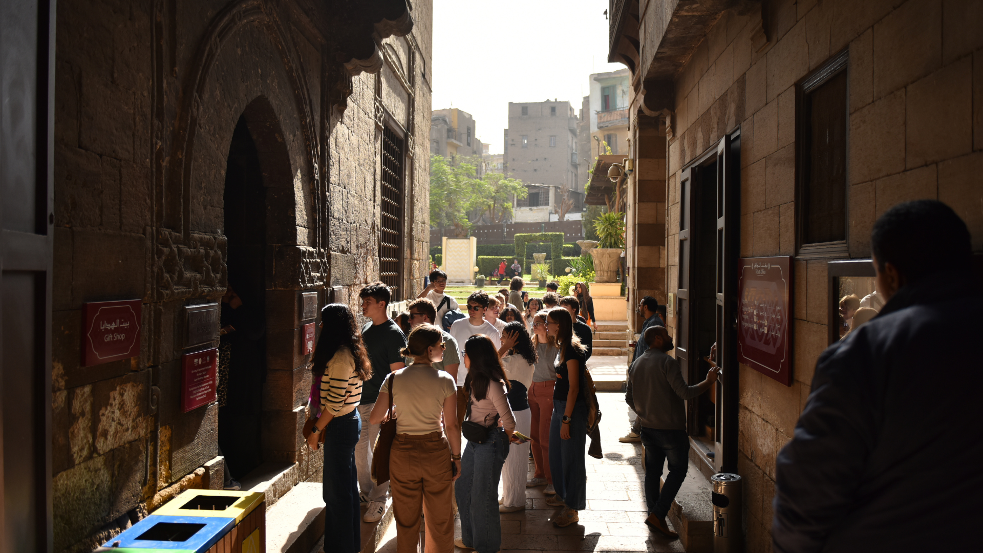 A group of students stands in an alleyway near a garden