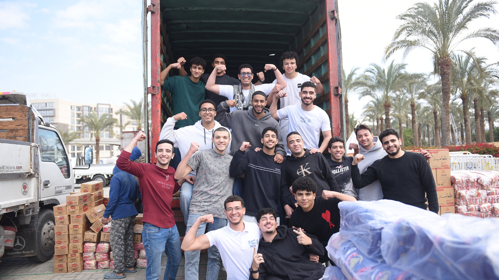 A group of young men stand in the back of a delivery truck flexing their arms