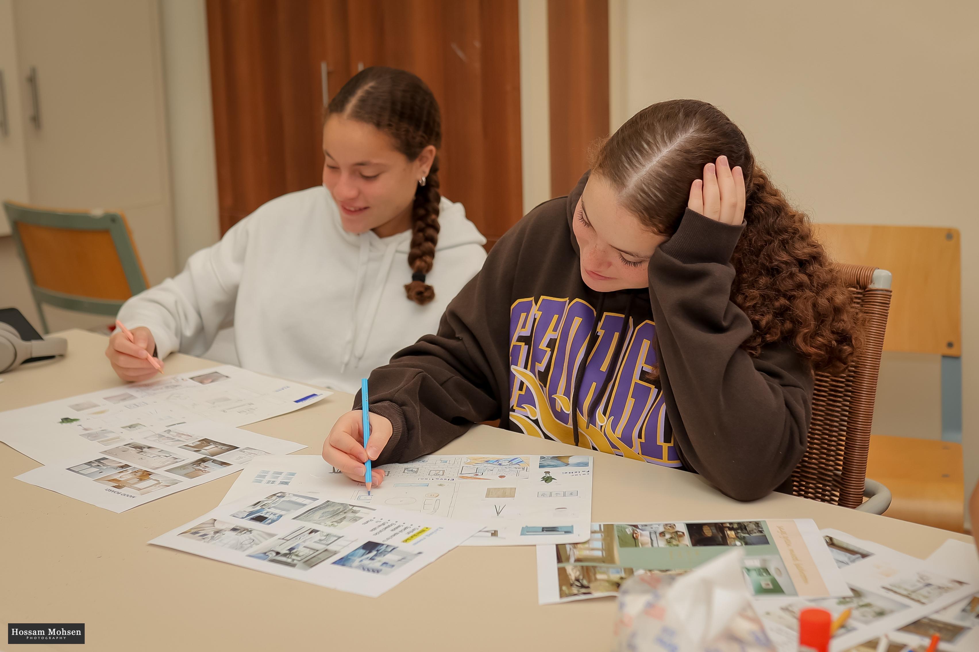 2 girls drawing interior sketches in class