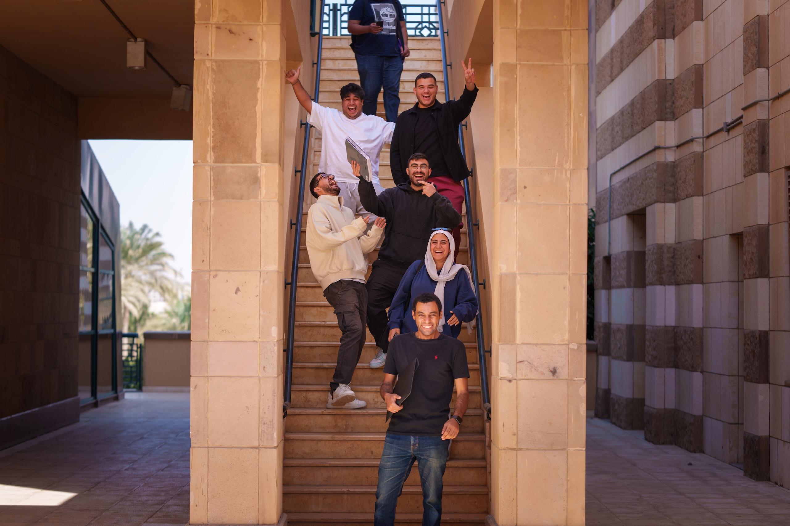 Males and a veiled female standing on stairs and laughing