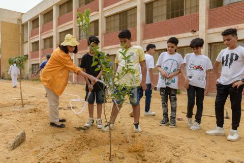 Professor plants trees with public school students in their playground