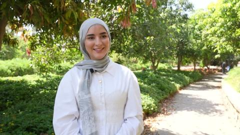 A veiled girl is smiling and standing in a garden