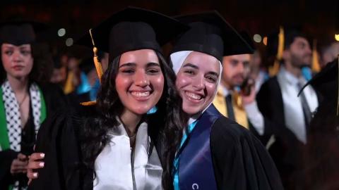Students during graduation wearing their caps and gowns and smiling