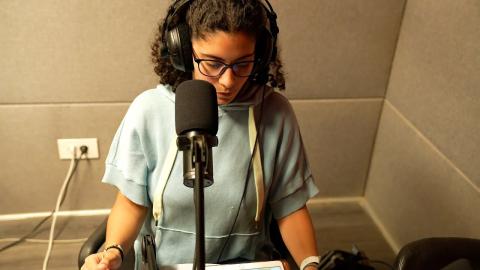 A female is wearing headphones and talking into a microphone