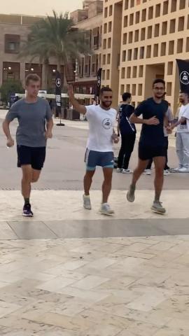 Three males are running. They are wearing sports shorts and t-shirts