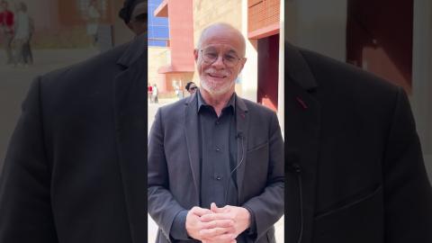 A man is standing and wearing a suit and glasses