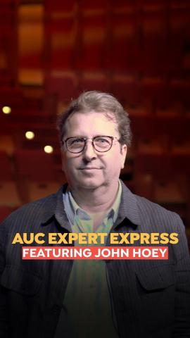 A man is smiling, he is wearing glasses and a brown jacket. Text: AUC Expert Express featuring  John Hoey