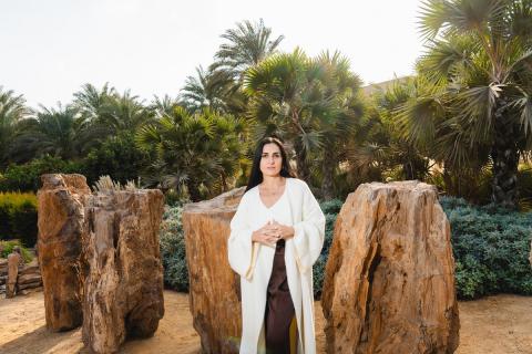 A woman is standing in front of big rocks