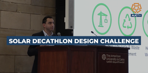 man standing at podium with text over screen 'solar decathlon design challenge'