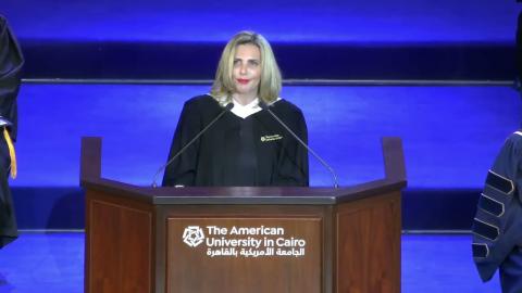 A female is talking at a podium, She is wearing a graduation gown. Text: The American University in Cairo