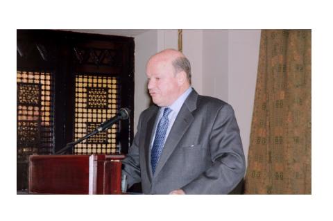 The late Ambassador Frank G. Wisner standing at an AUC podium and speaking into the microphone