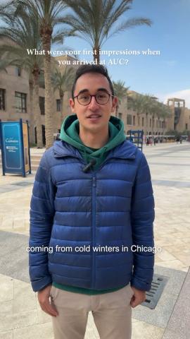 A male is standing and smiling. Text: What were your first impressions when you arrived at AUC?