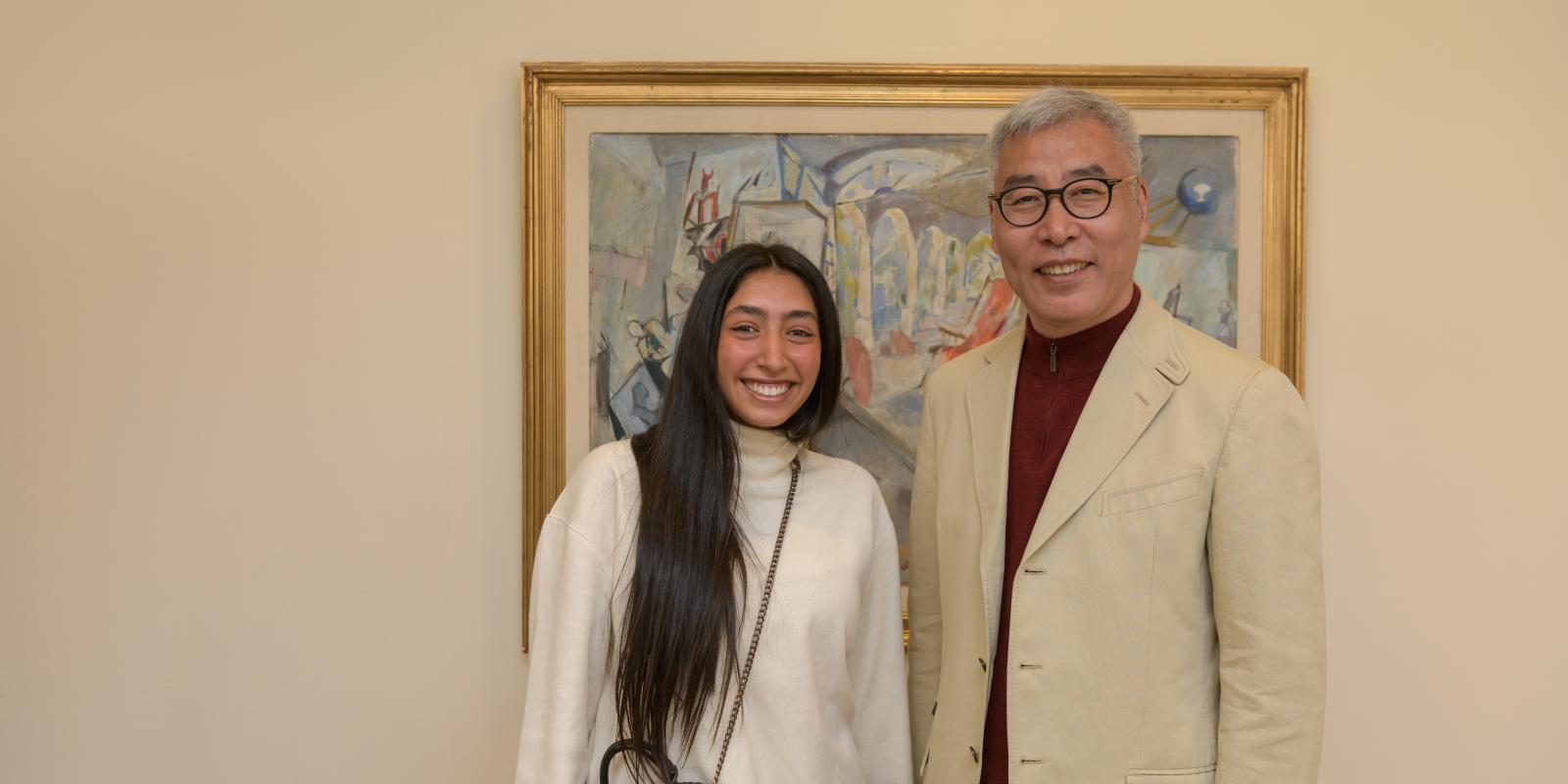 Shahd El Helbawy stands with Wei Liu, smiling in front of a painting.