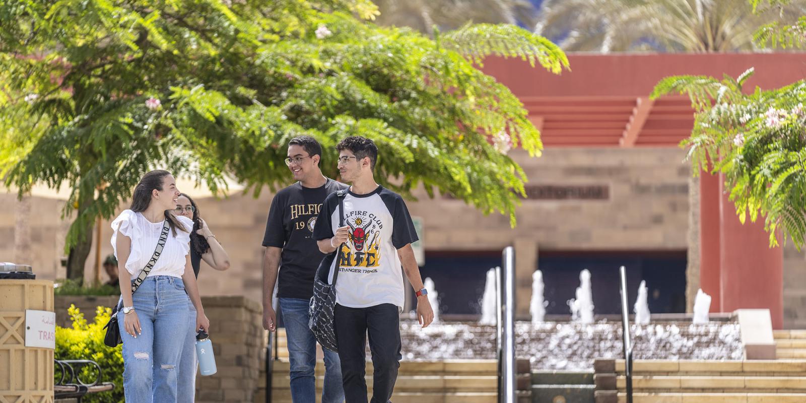 A group of girls and boys walking on campus infornt of Bassily Auditoriam