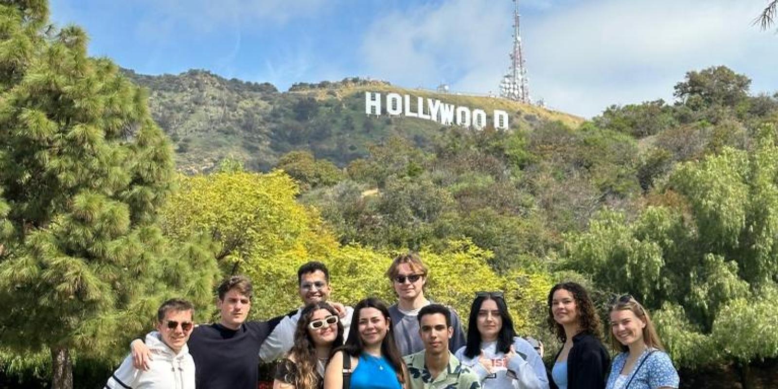 A group of girls and boys taking a picture infront of Hollywood sign outdoors