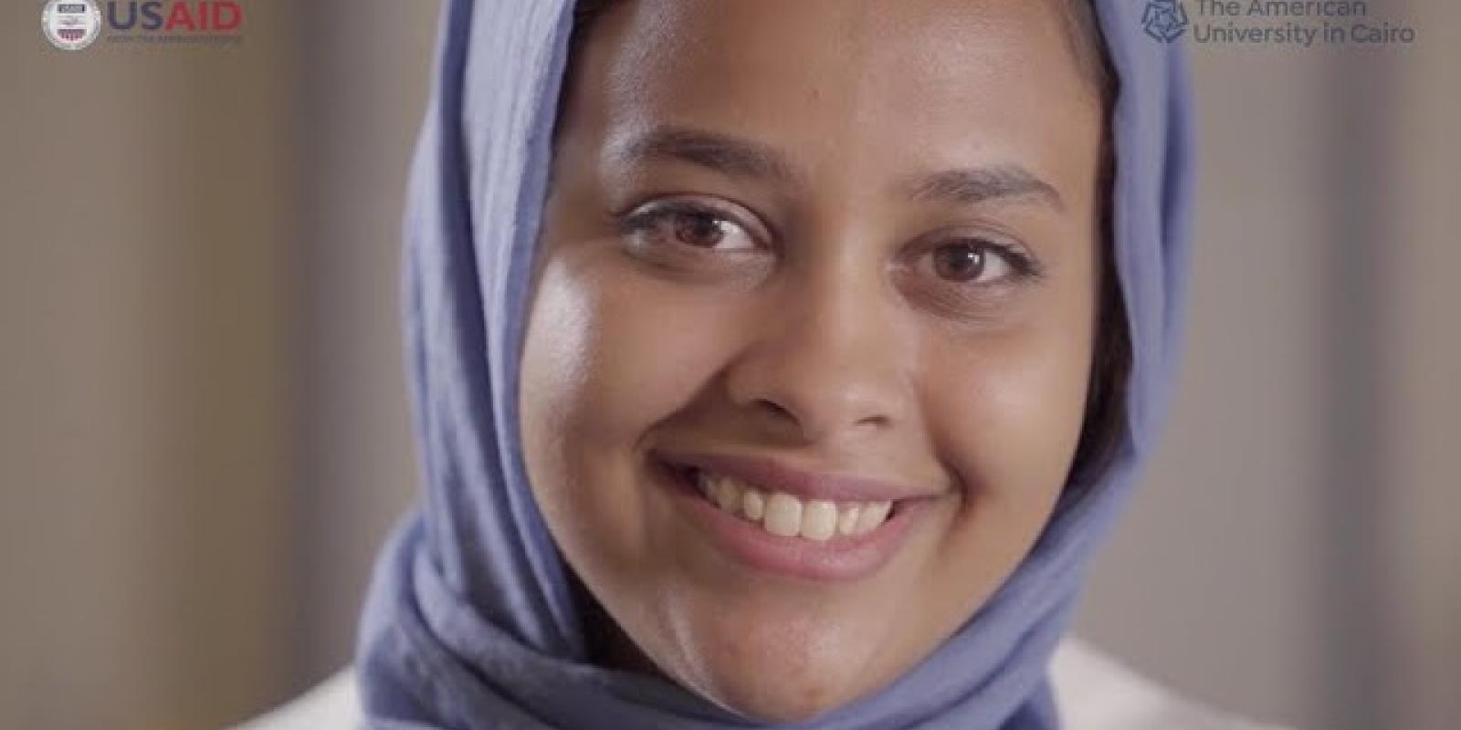 A girl smiling, text reads "The American University in  Cairo and USAID"