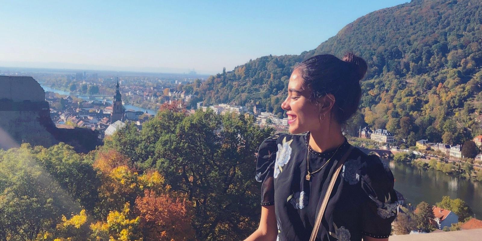 Woman smiles overlooking a city and lush green trees