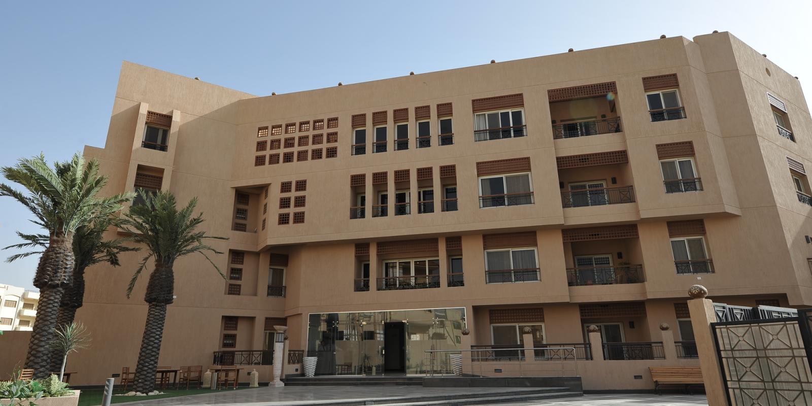 Tall beige building with palm trees