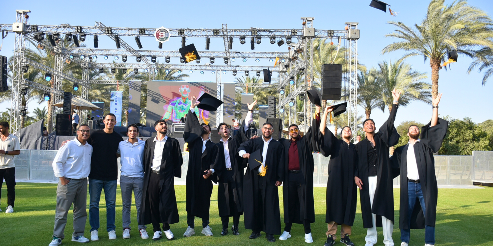 Students stand together throwing their graduation caps