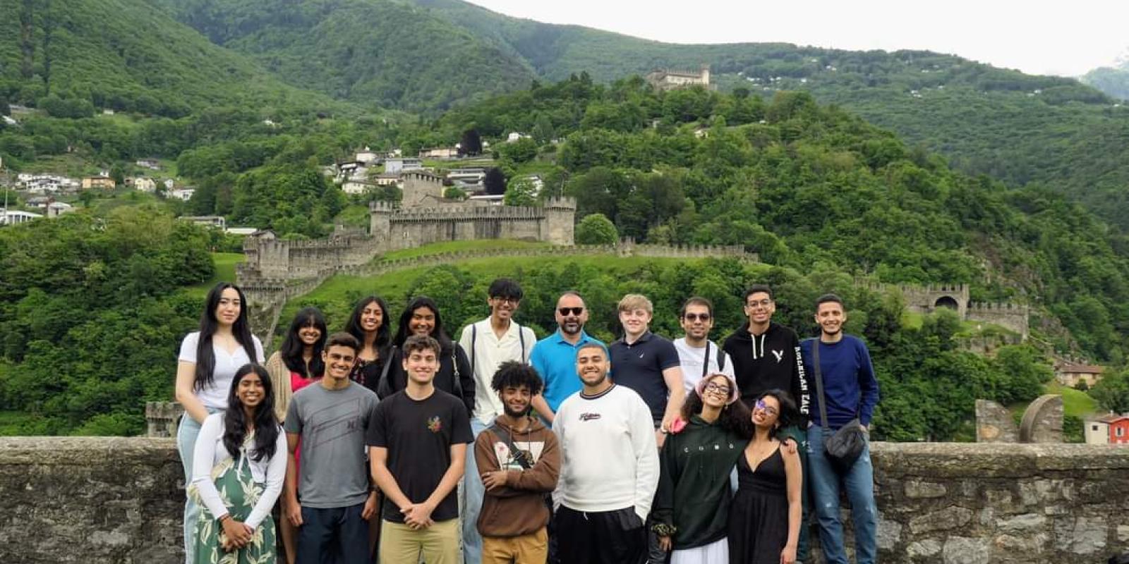 A group of students pose in front of green mountains