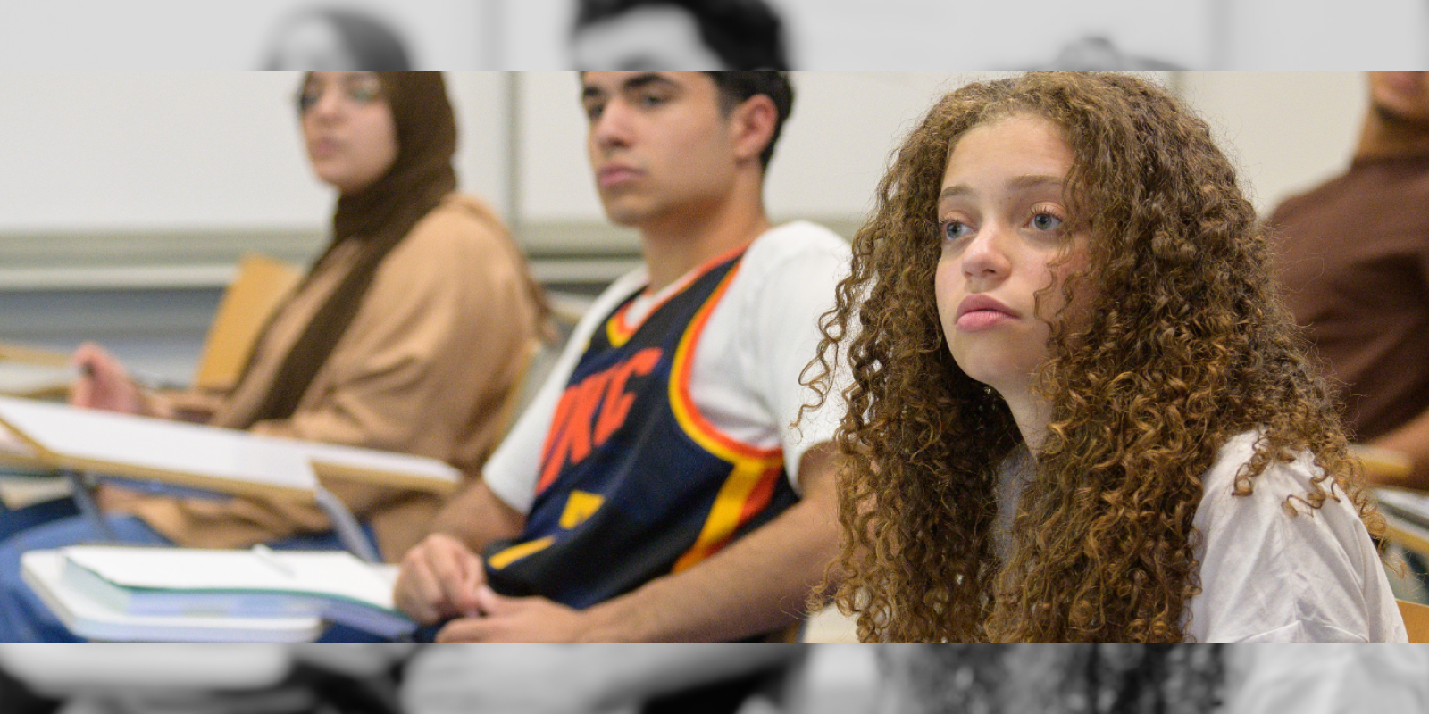 Students in class sitting at their desks and looking straight