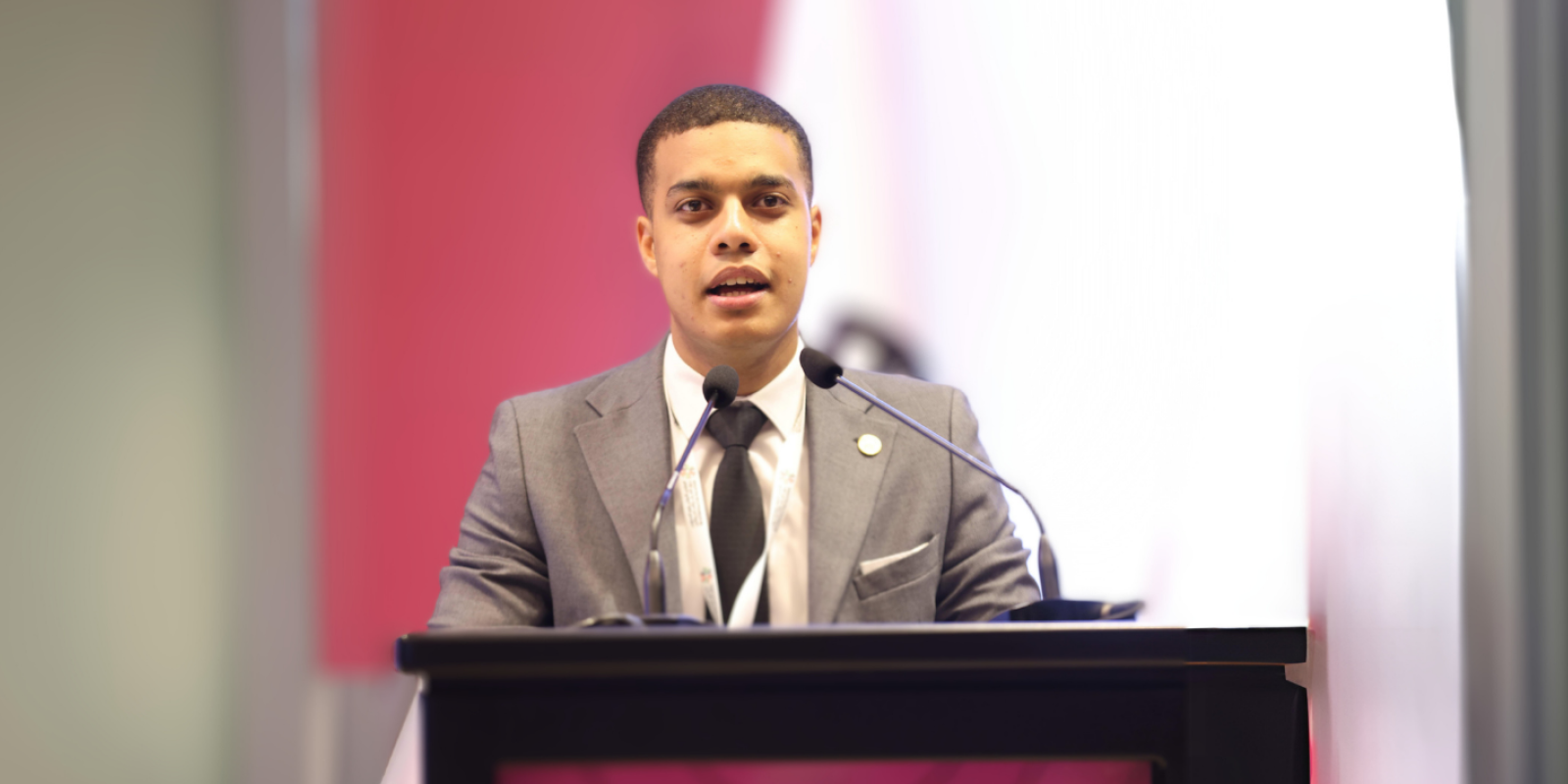 Student wearing a suit and speaking at a podium