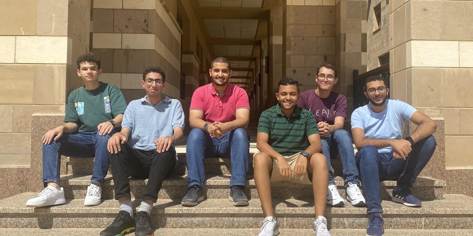 Six males sitting on outdoor stairs 