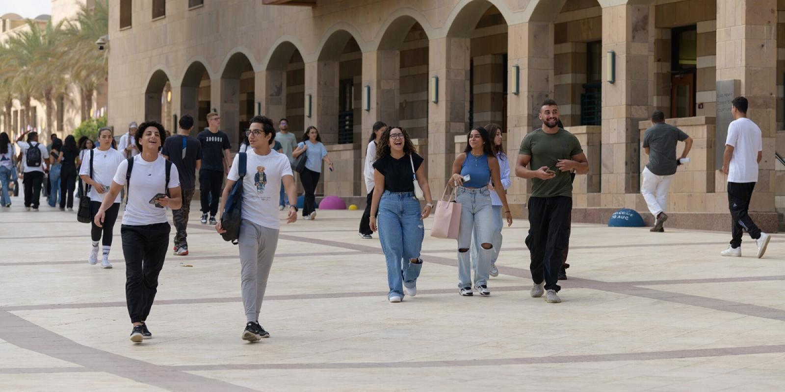 Males and females walking next to a building