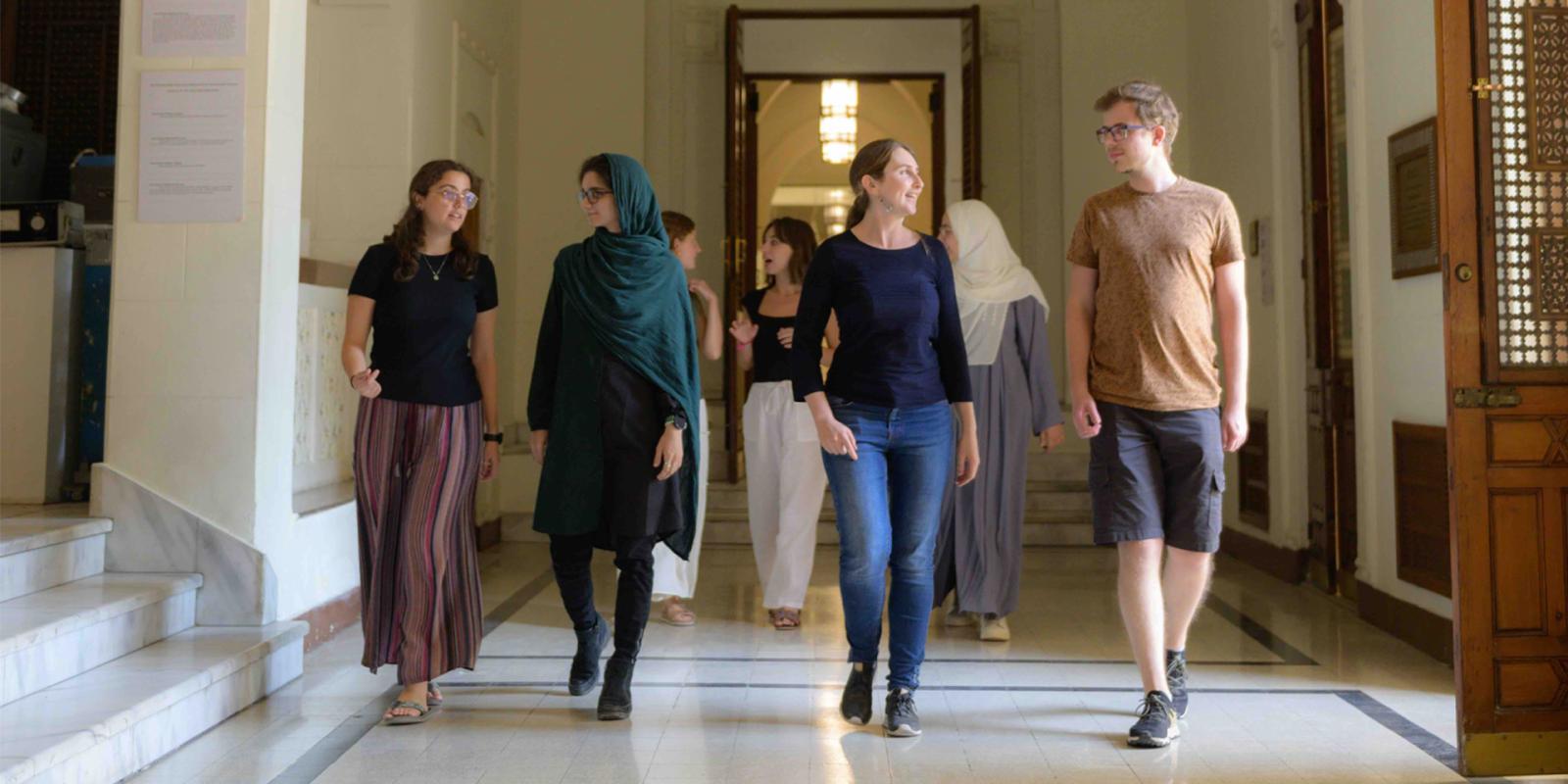 A group of international students from the CASA@AUC program are walking and smiling together in the historic palace at AUC Tahrir Square.