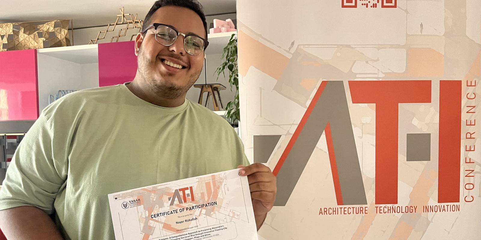 An AUC architecture student smiling and hoding a conference certificate and standing in front of the conference backdrop in Turkey