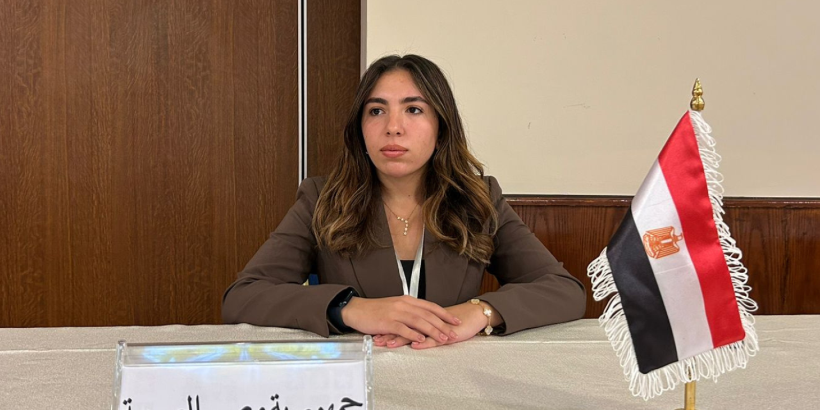 Maysem Alagamy sitting behind a mini Egyptian flag and placard