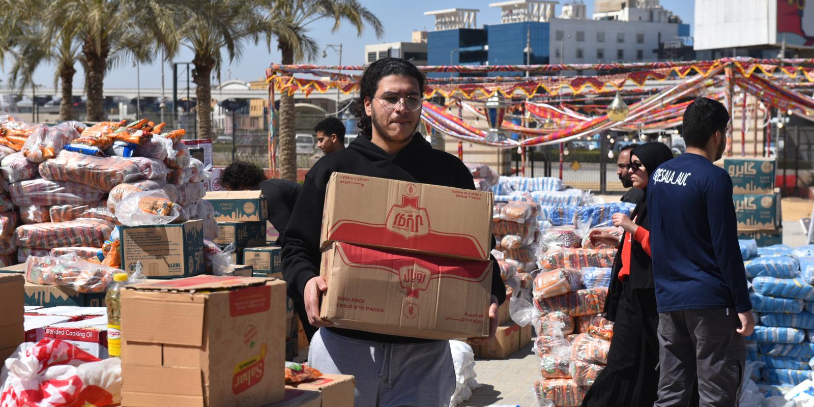 A student carries a box in the midst of piles of packaged food boxes