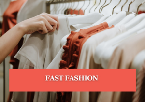 A person's hand looking through clothes hanging on a clothes rack