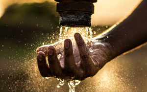 Hand touching water from a faucet