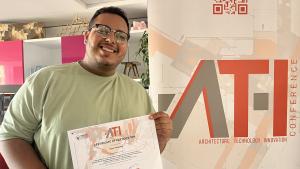 An AUC architecture student smiling and hoding a conference certificate and standing in front of the conference backdrop in Turkey