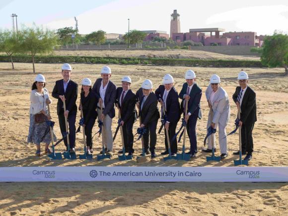 A group of men and women holding shovels on a step. Text: Campus 2026 Groundbreaking. The American University in Cairo