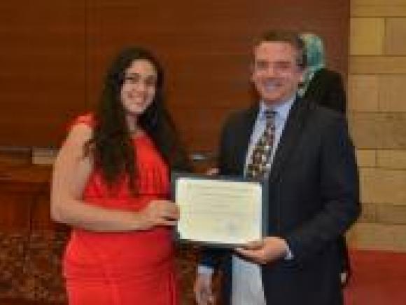 A female is holding a certificate with professor Adham Ramadan