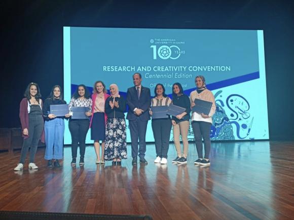 Female student holding certificates with AUC Provost Ehab Abdel Rahman